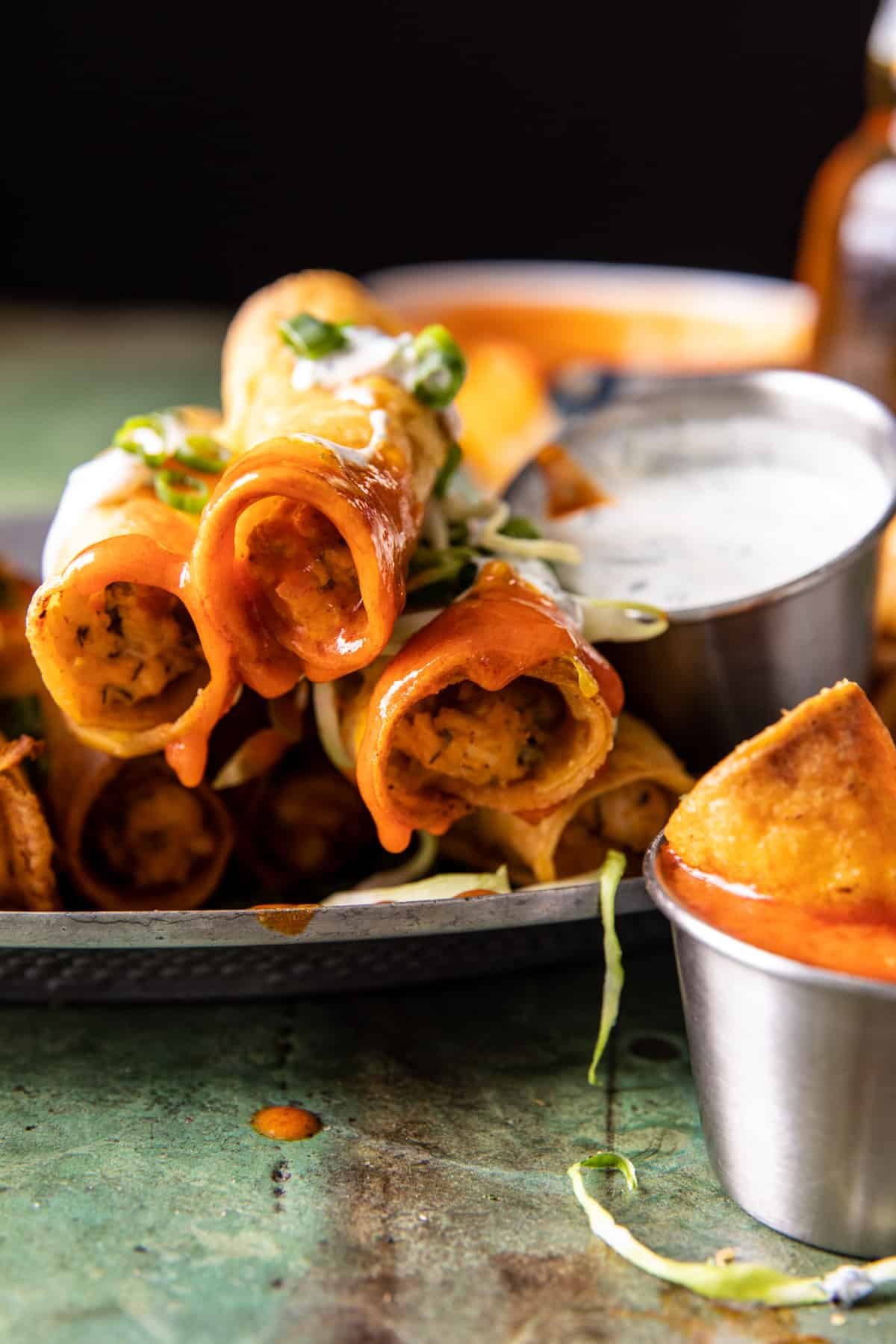 taquitos stacked with buffalo sauce dripping off