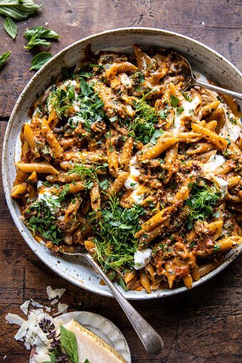 overhead photo of sun-dried tomato pasta in serving bowl with parmesan on table